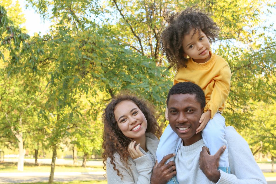 Un père porte son enfant sur les épaules, tous deux rient