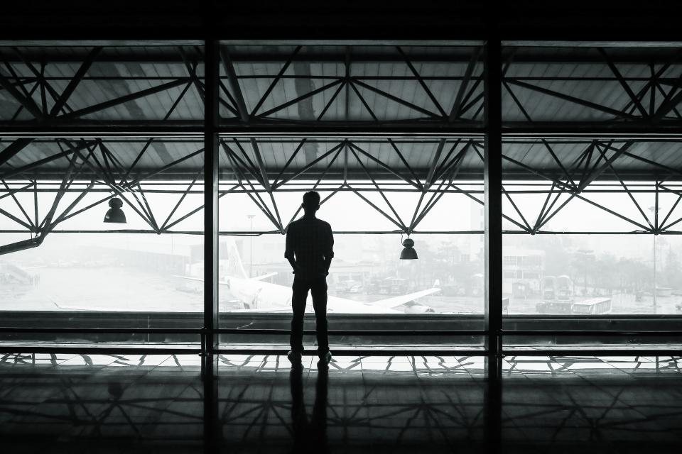 Une personne regarde les avions derrière la baie vitrée d'un aéroport